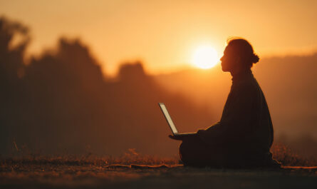 Bild zu: KI – kreative Intelligenz? Das Bild zeigt die schemenhafte Darstellung eines Menschen in der Natur, mit einem Notebook auf dem Schoß, vor einem Sonnenuntergang. (c) Copyright: Bild: Adobe Stock, Bildnummer: 2038303697
